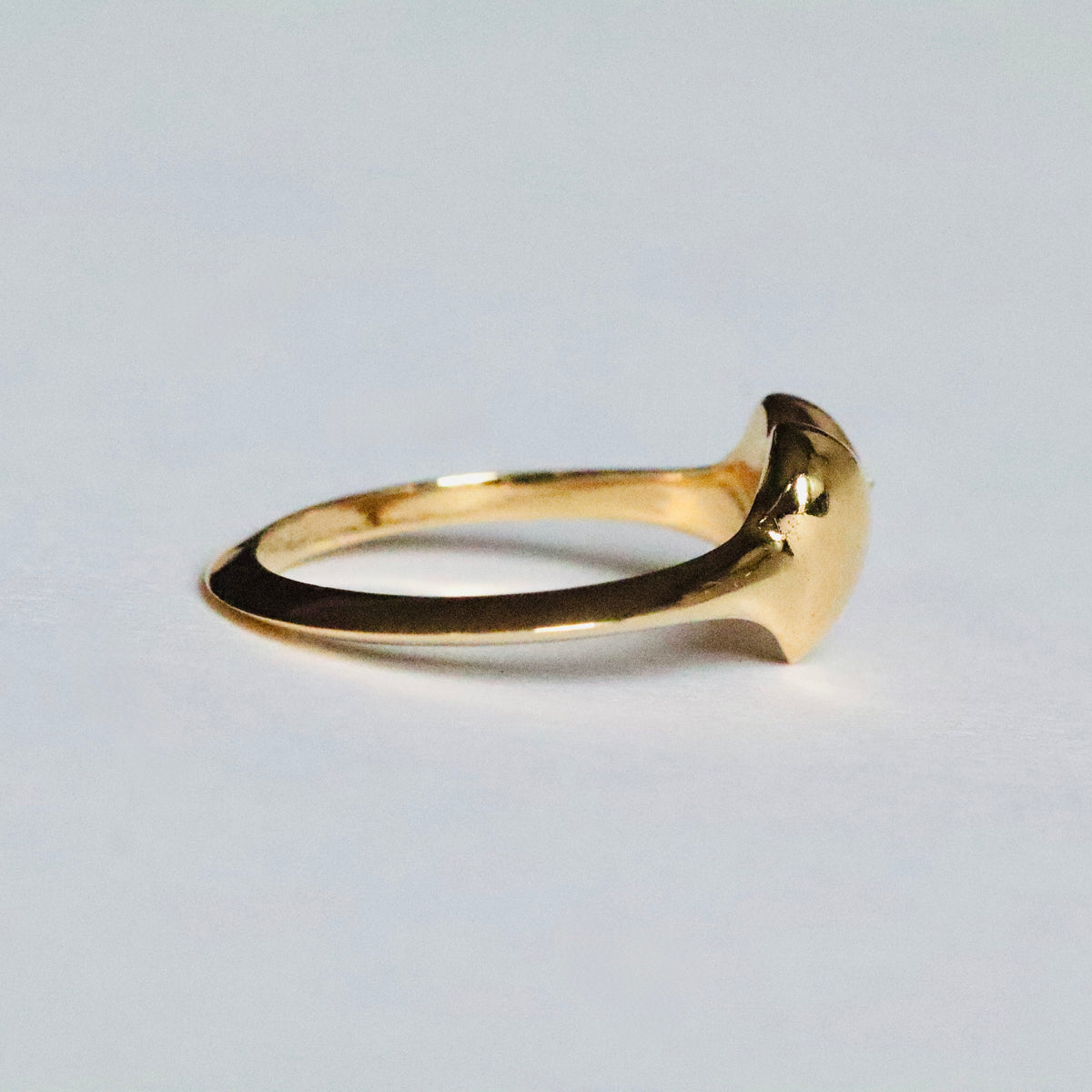 Gold heart-shaped signet ring by Tamsin Rasor, with a star set spiked diamond on the right hand side, shown from the side against a white background