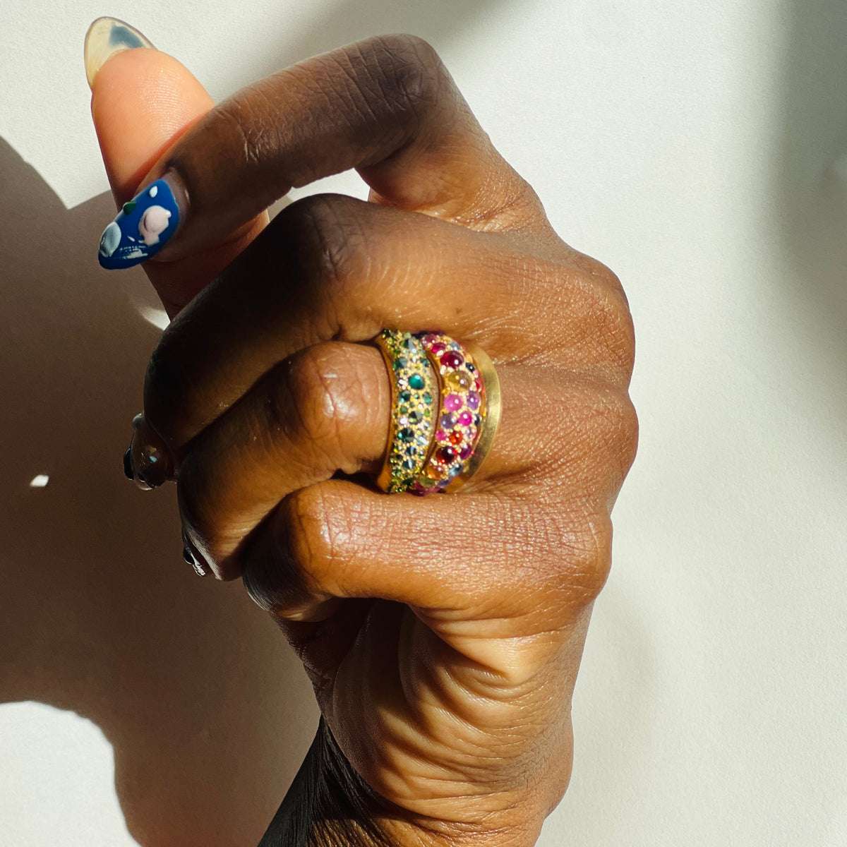 Green diamond Duomo ring and Jelly Bean Duomo ring on models ring finger on white background