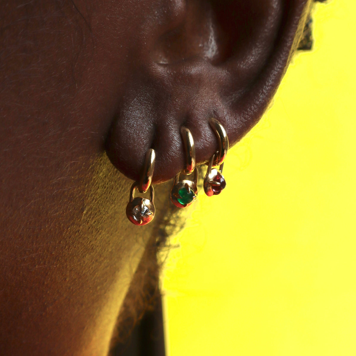Three Mini Compass Hoop Earrings on Models ear with neon yellow background