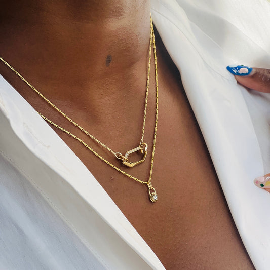 Mini gold and diamond compass necklace stacked with Makhaira link necklace on model wearing white shirt, by Tamsin Rasor