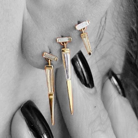 Three yellow gold drop earrings with baguette cut diamonds, by Tamsin Rasor, shown on models ear