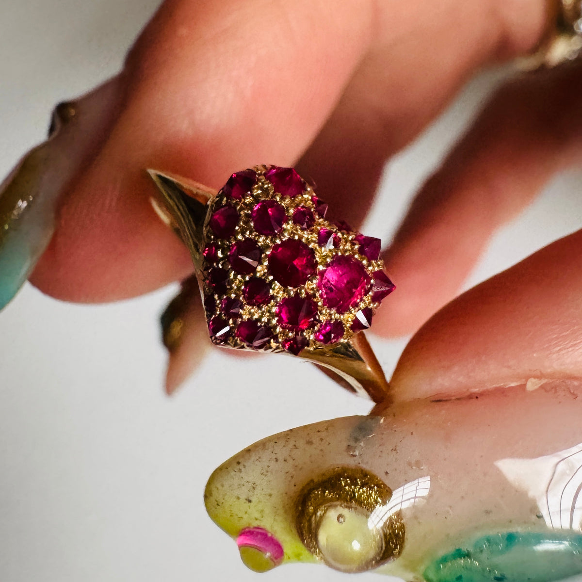 gold and spiked pavé ruby heart shaped signet ring by Tamsin Rasor shown in between models thumb and index finger