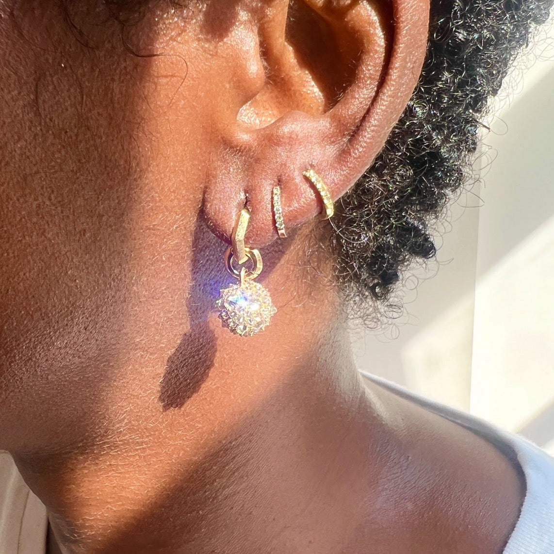 close up of gold and diamond earrings on models ear