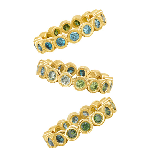 Three sides of the same blue and green ombré color diamond eternity ring in yellow gold bezel setting, by Tamsin Rasor on white background