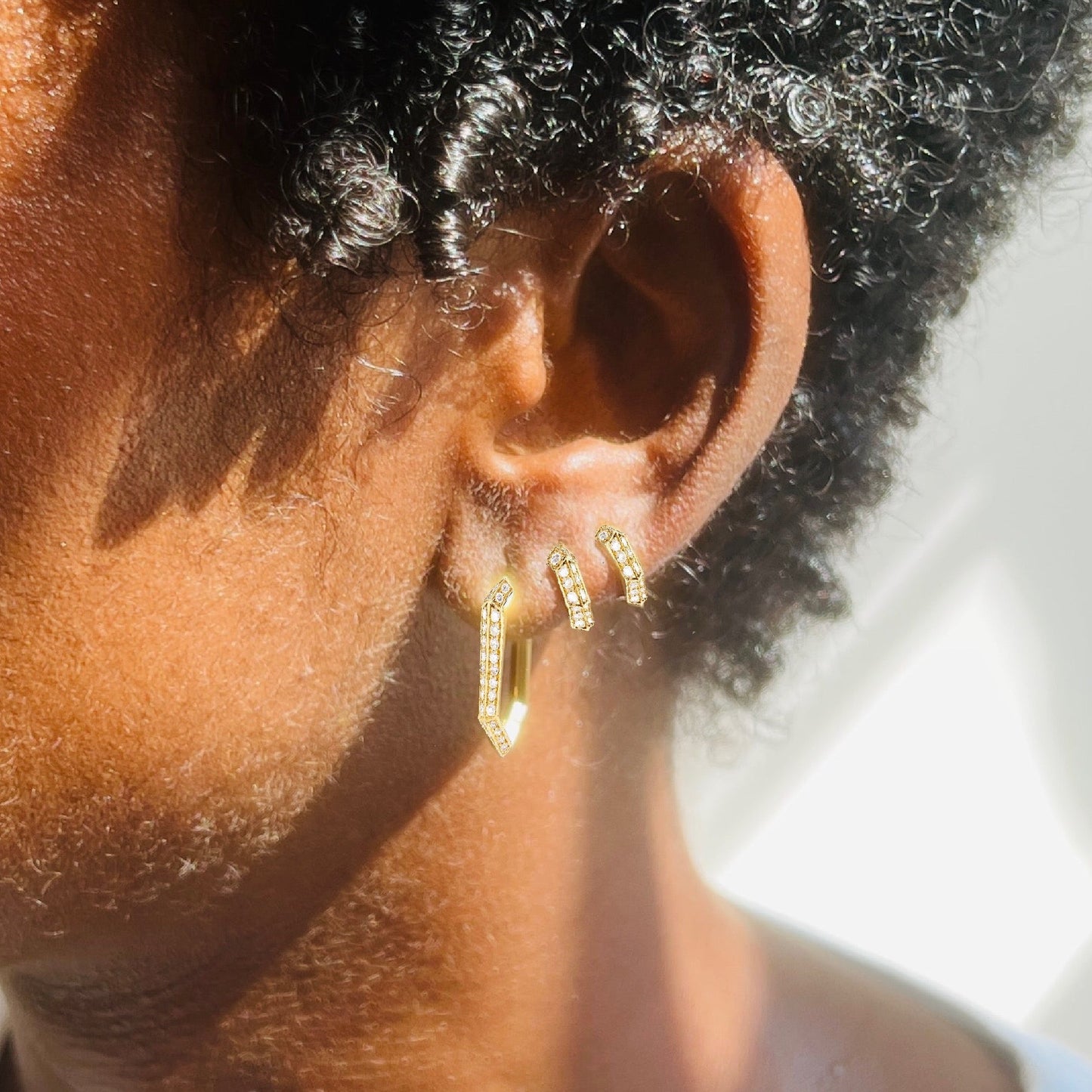 Close up of diamond and gold Makhaira hoop earrings on models ear