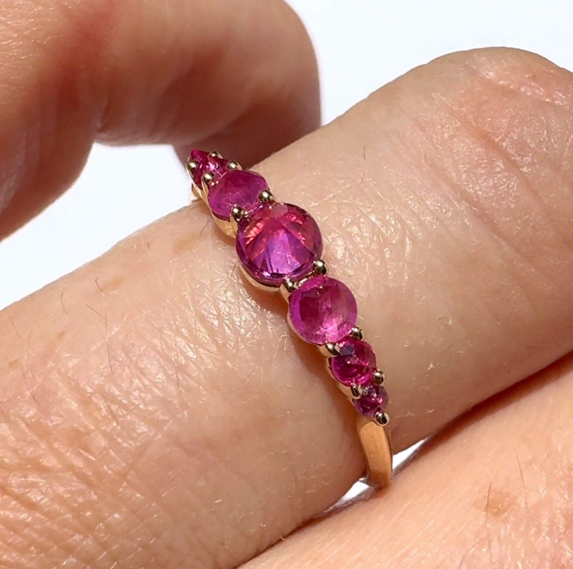 Spiky seven stone ruby and gold ring , on models fonger against white background by Tamsin Rasor 