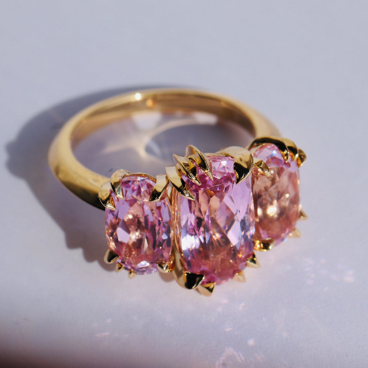 Large cocktail ring with three pink Kunzite gemstones and asymmetric knife edged gold setting, shot from above, by Tamsin Rasor, on a white background