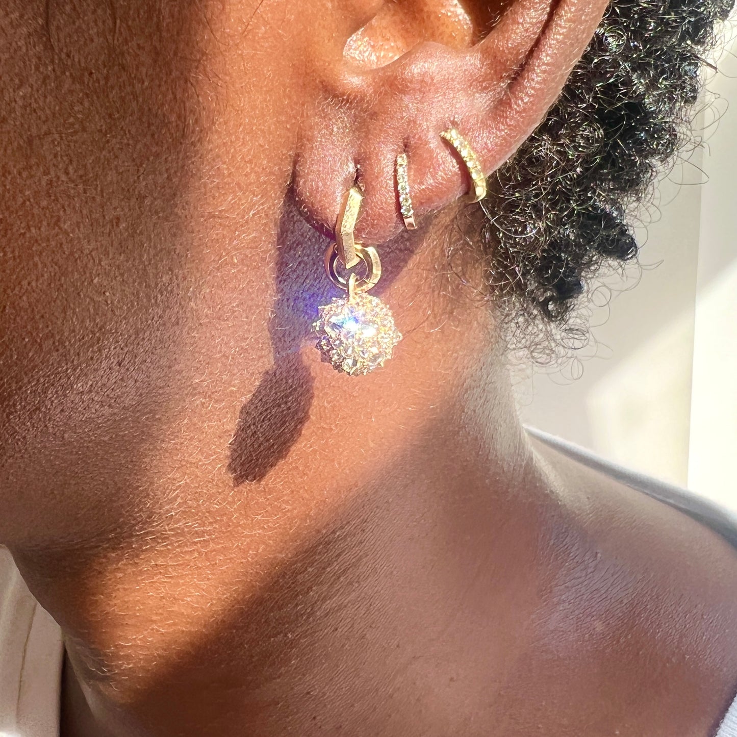 gold and diamond orb charm hung from gold hoop earring on model