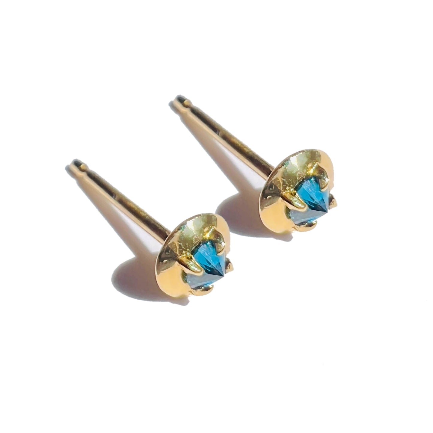 Barbed teal diamond studs on a white background