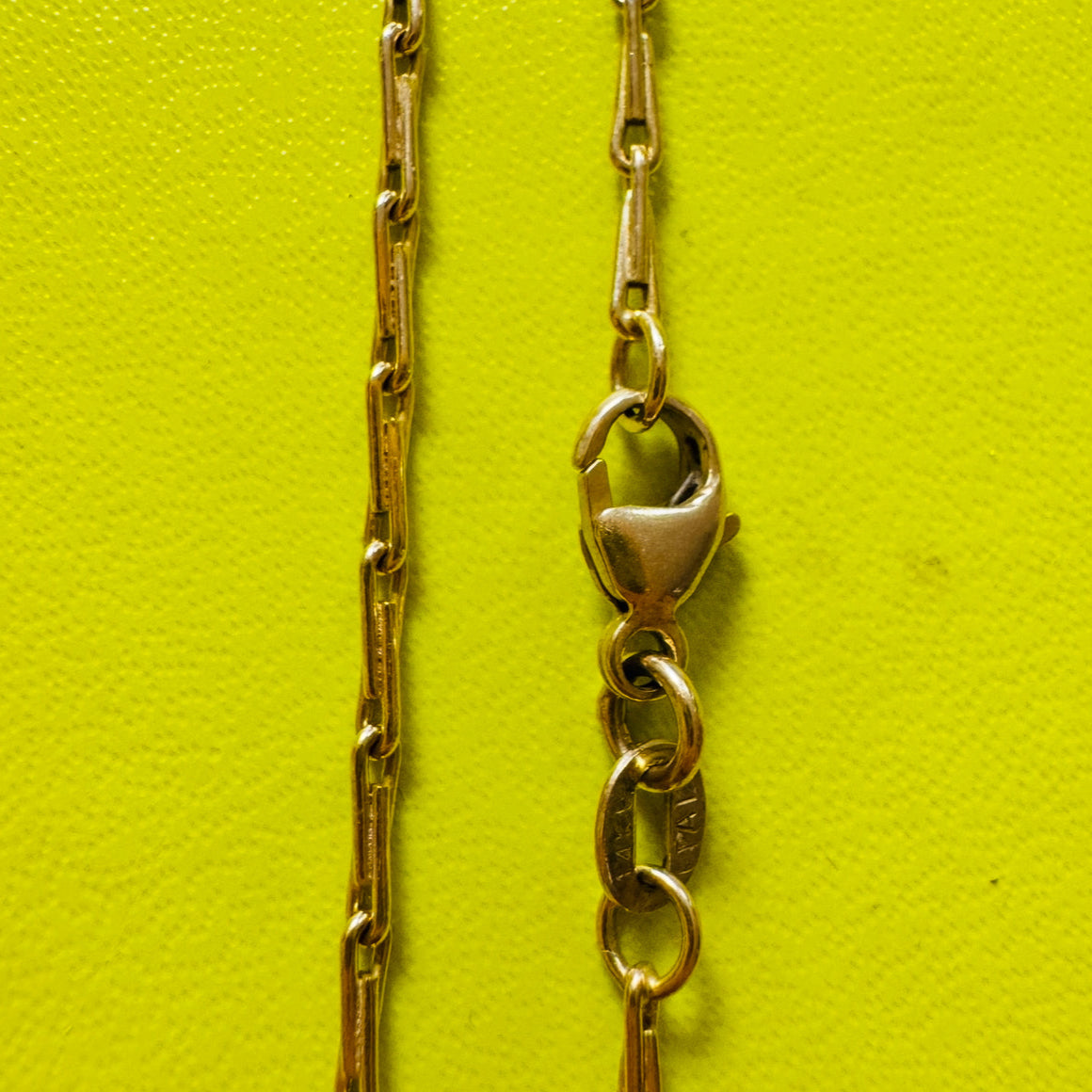 close up of gold barley corn chain 1.7mm wide on and spring lobster clasp on yellow background by Tamsin Rasor Fine Jewelry