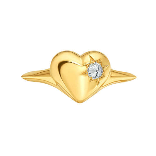 Gold heart-shaped signet ring  by Tamsin Rasor, with a star set spiked diamond on the right hand side, shown against a white background