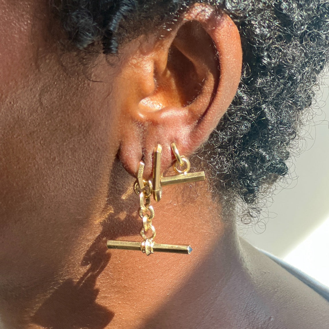 gold earrings with t-bar charms on models ear