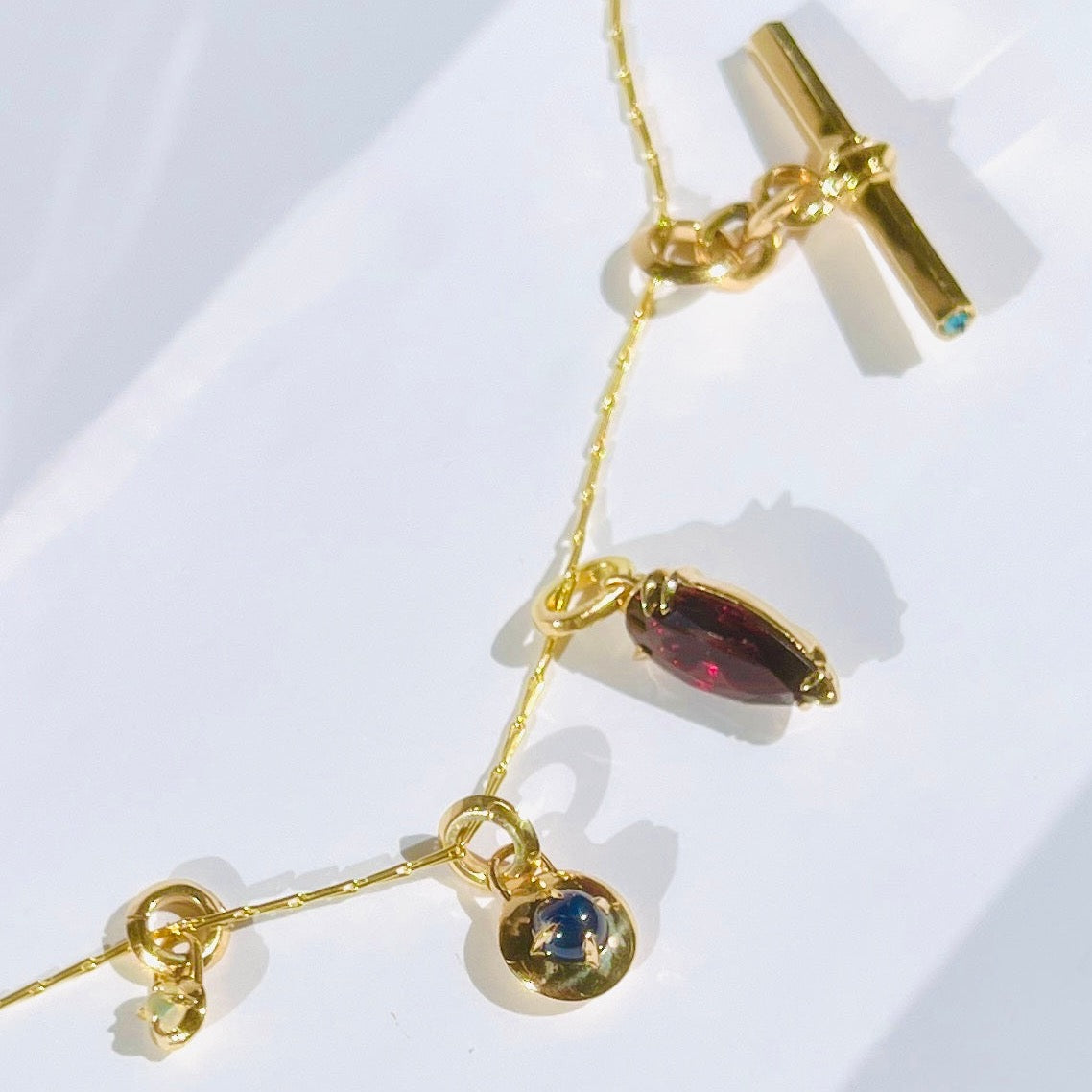 four gold charms on a chain by tamsin rasor against white background