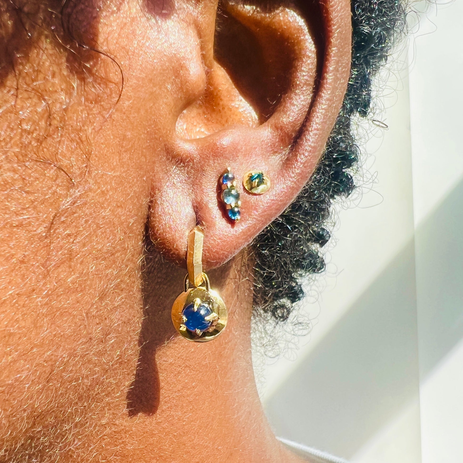 Three sapphire and diamond earrings on models ear