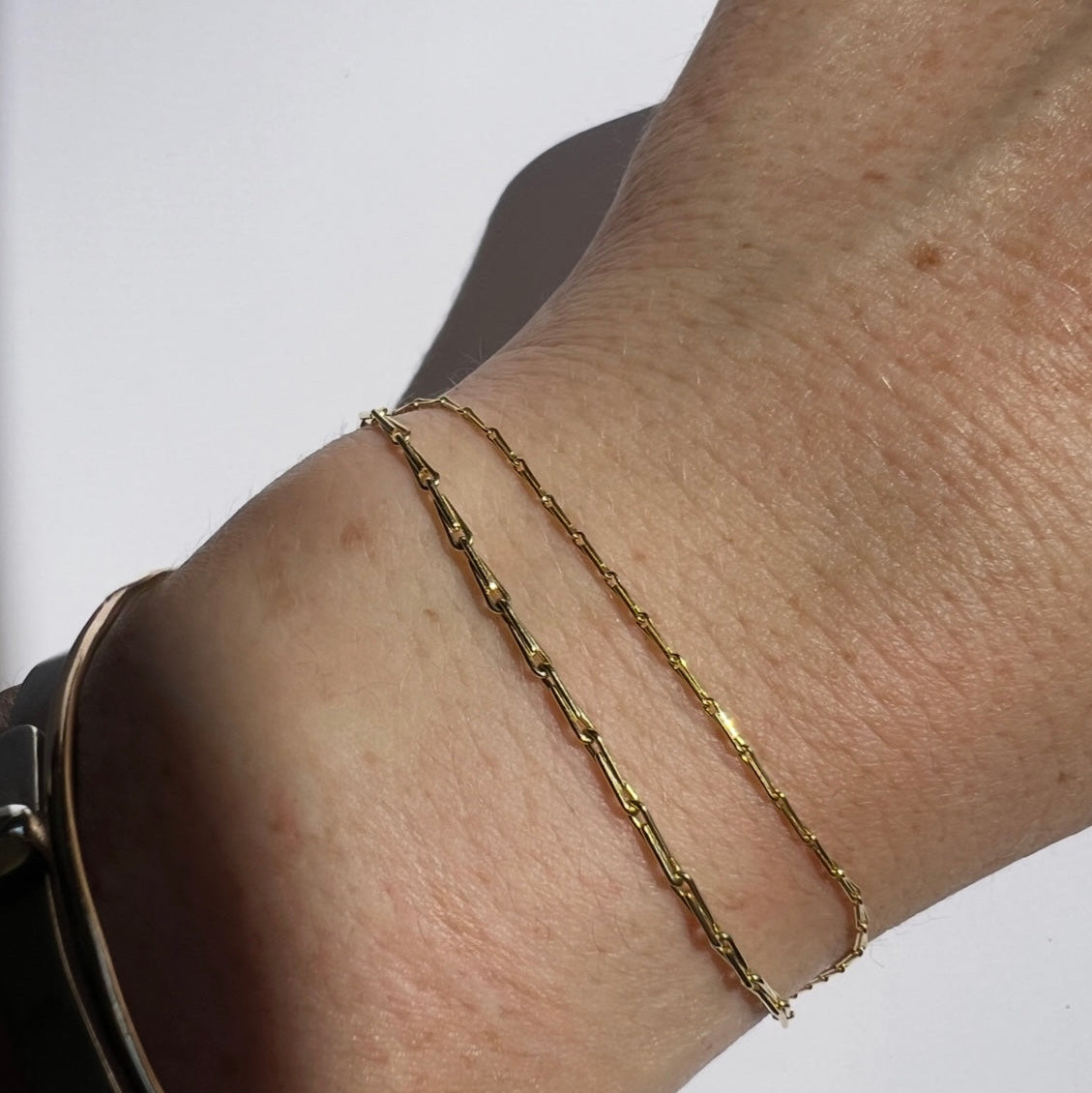 gold barley corn chain in 1mm and 1.7mm widths shown on models wrist against a white background by Tamsin Rasor Fine Jewelry