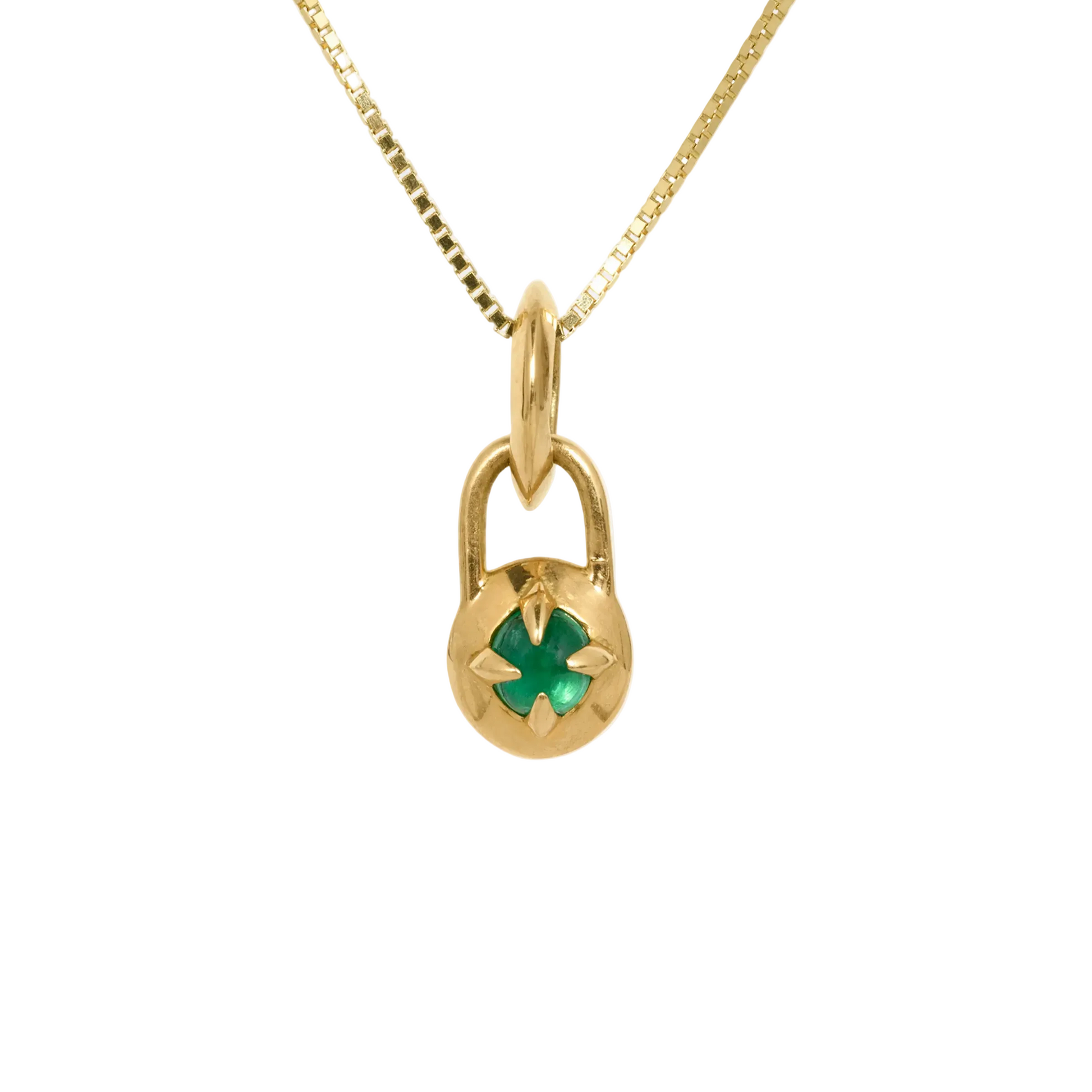 Gold necklace with a compass pendant featuring a natural emerald cabochon against a white background by Tamsin Rasor