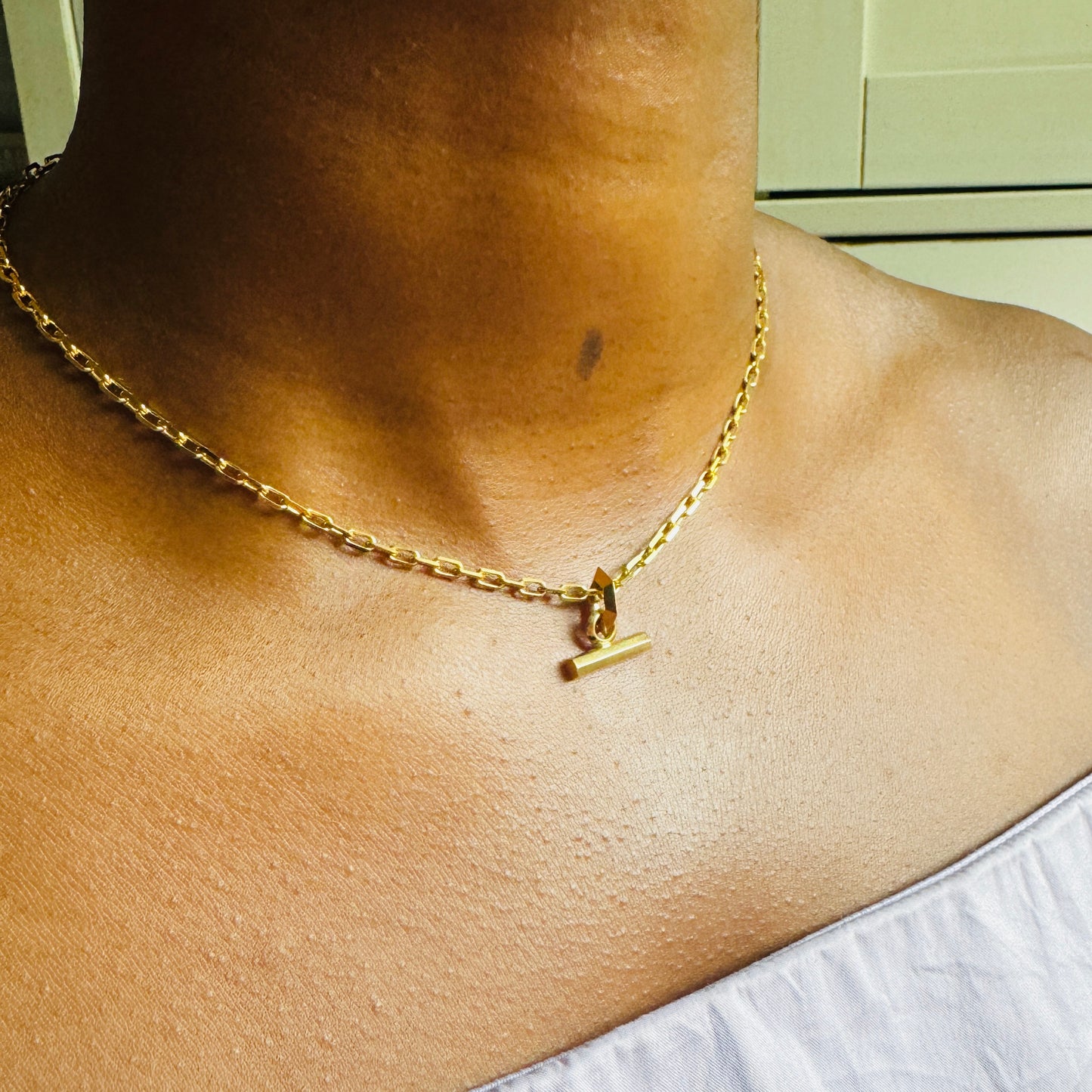 Small Gold T-Bar pendant on chunky gold chain by Tamsin Rasor on model wearing lilac top against white background