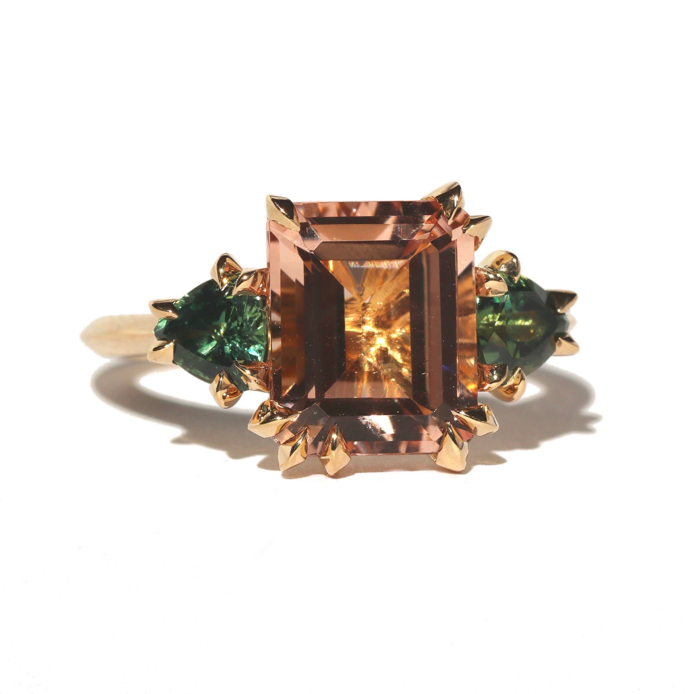 Morganite and green sapphire three stone Makhiara Trilogy ring by Tamsin Rasor in 18K gold on a white background 