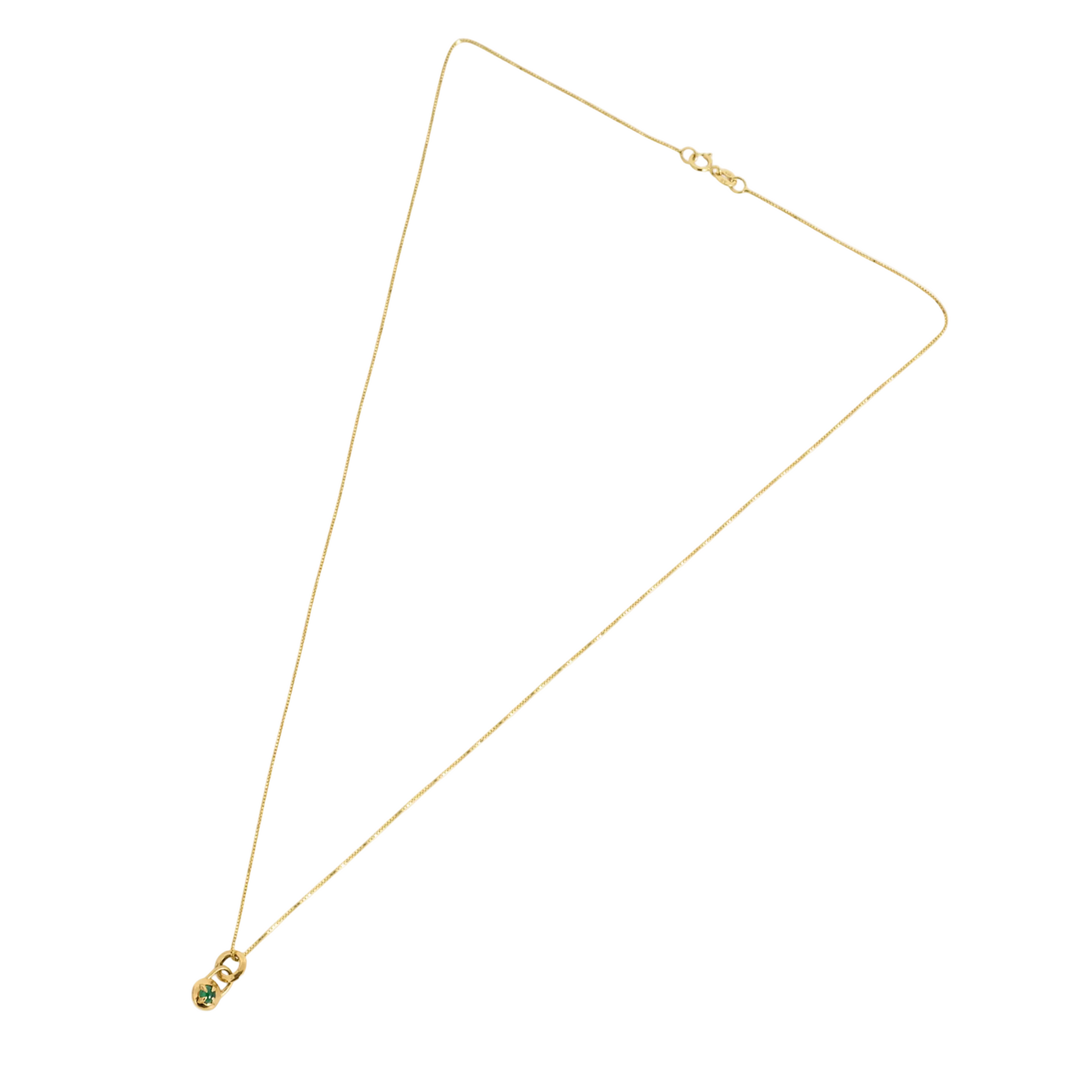 Flat lay of a gold necklace with a compass pendant featuring a natural emerald cabochon against a white background by Tamsin Rasor