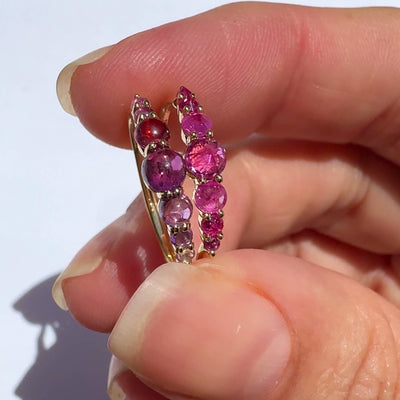 Spiky seven stone ruby and gold ring ,and cabochon ruby and gold ring in models fingers, against white background by Tamsin Rasor 