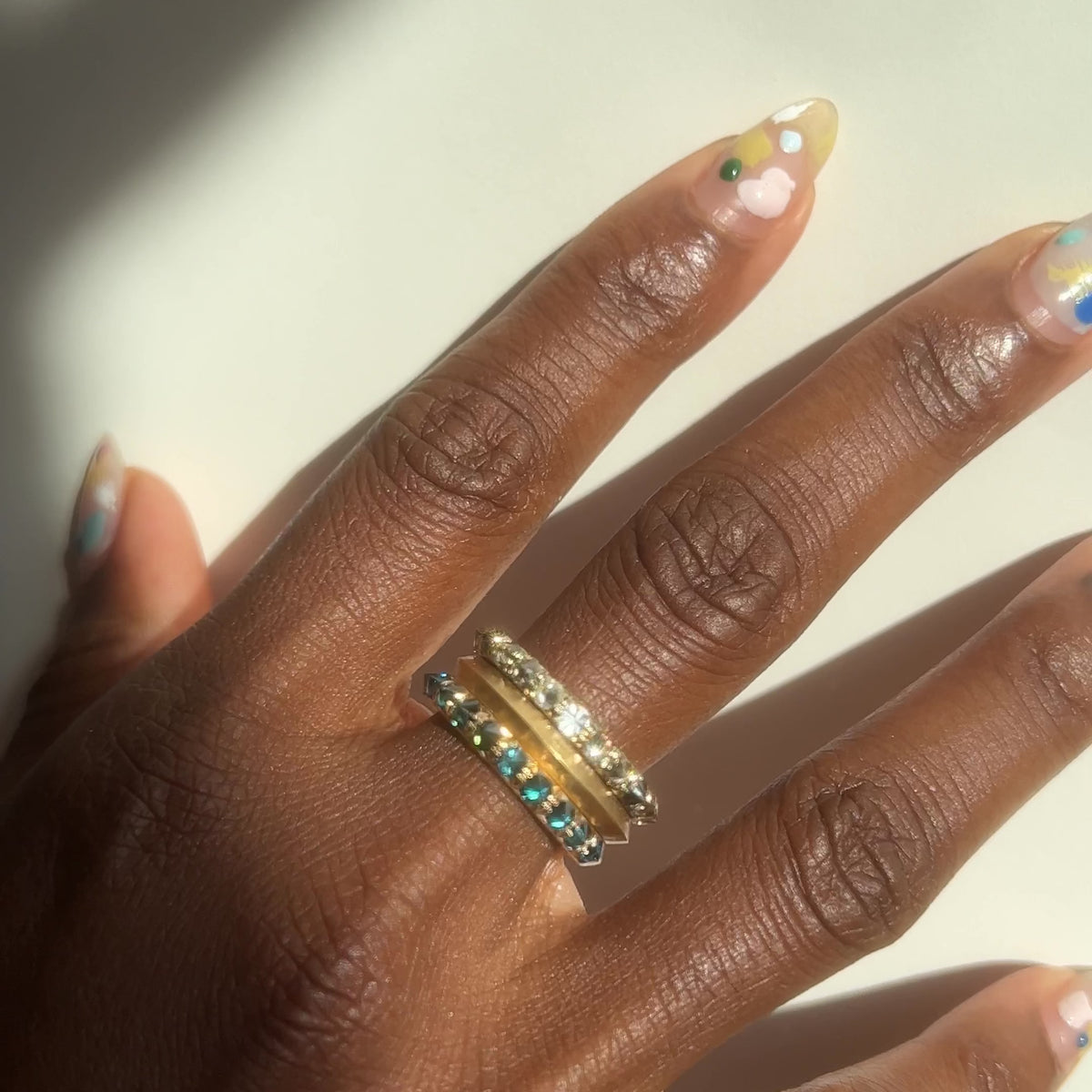 Barbed Diamond half eternity rings in blue and white diamond , stacked with knife edge gold band on models middle finger by Tamsin Rasor