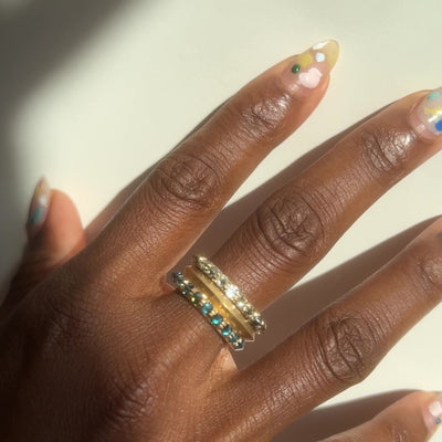 Barbed Diamond half eternity rings in blue and white diamond , stacked with knife edge gold band on models middle finger by Tamsin Rasor