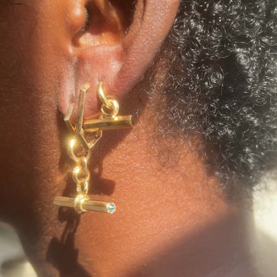 Three gold T-bar fob charm and hoop earrings by Tamsin Rasor on Model's ear