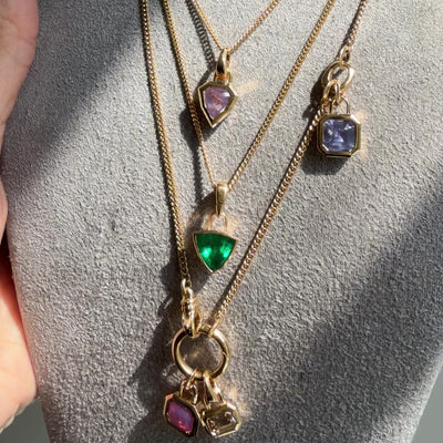 Video of 18K yellow gold and color gemstone bezel set pendants on chains by Tamsin Rasor, shown on grey neck form in the sun shine