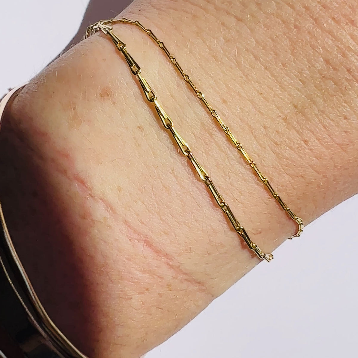 video of gold barley corn chain in 1mm and 1.7mm widths shown on models wrist against a white background by Tamsin Rasor Fine Jewelry