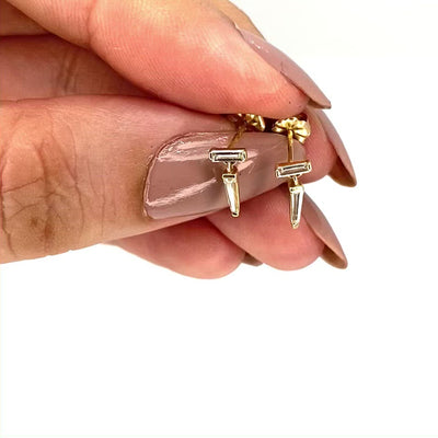 vidoe of a pair of yellow gold drop earrings with baguette cut diamonds, by Tamsin Rasor, in models hand, against a white background