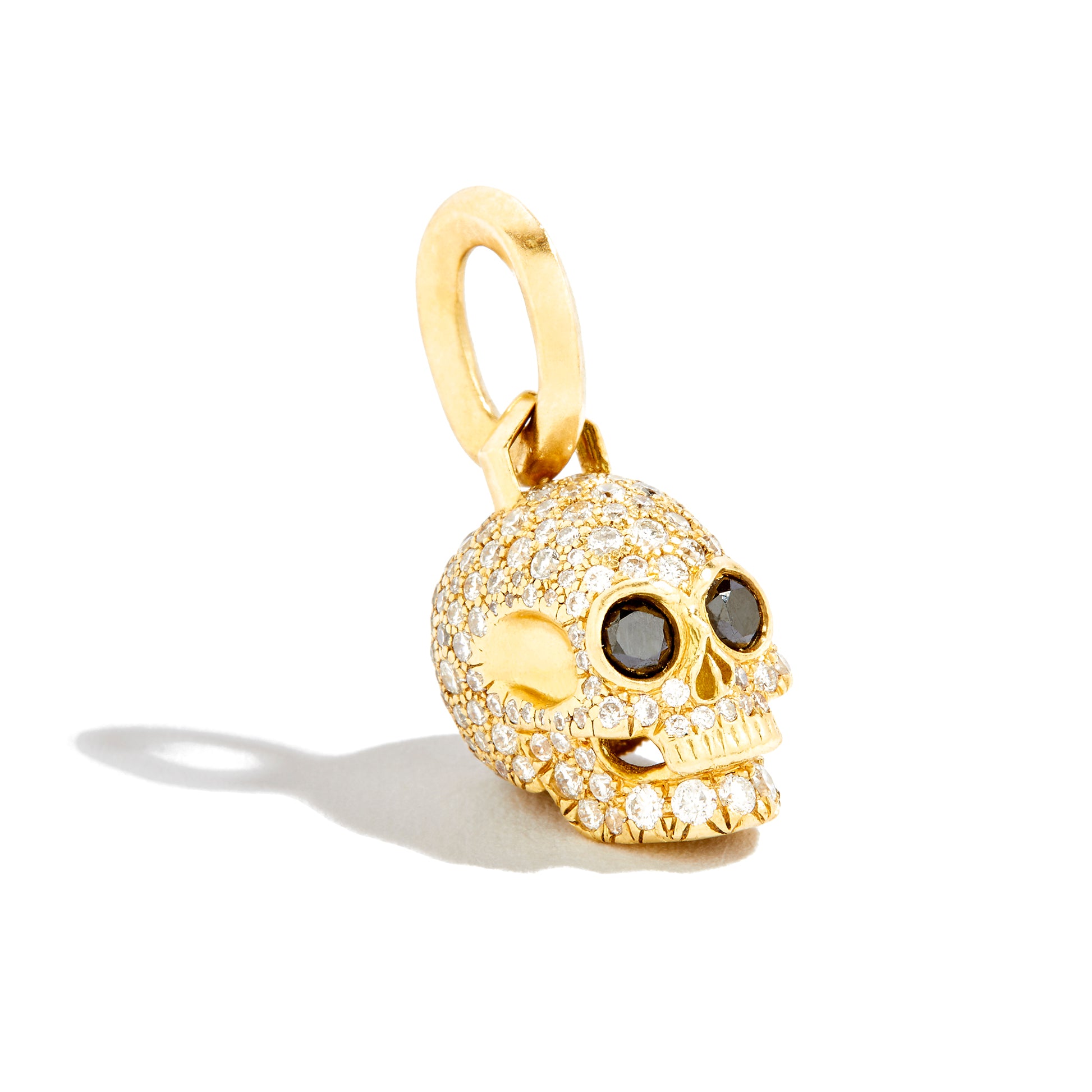 All Over pavé diamond and yellow gold skull pendant with black diamond eyes on white background